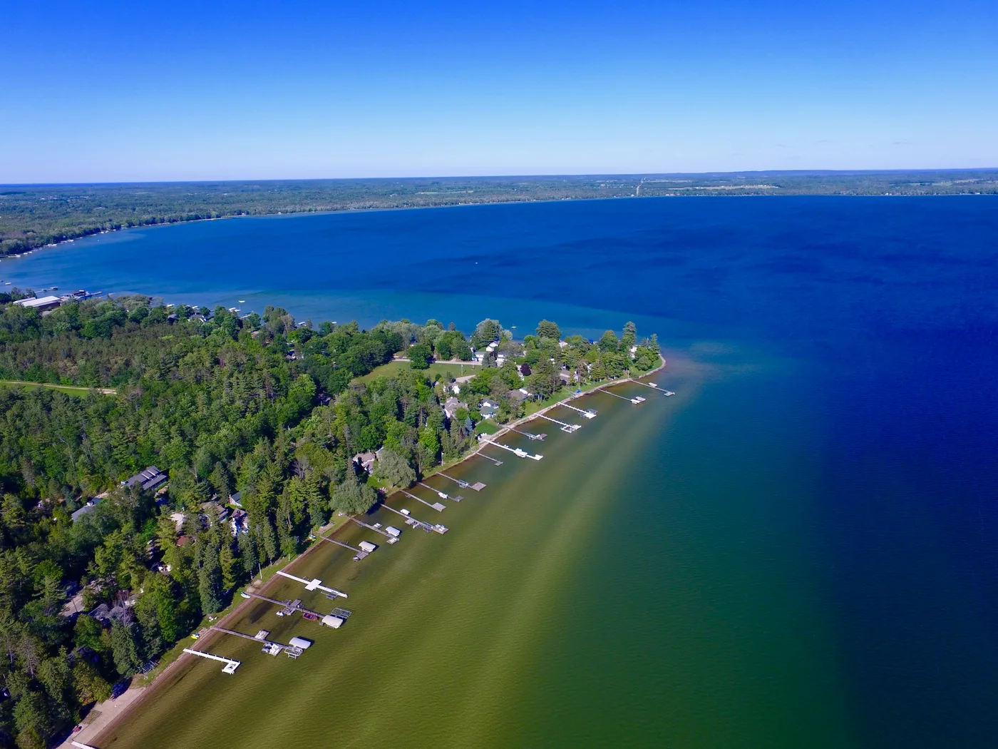 Aerial view of cottage docks and boats reaching into the deep blue water of Mullett Lake, Michigan