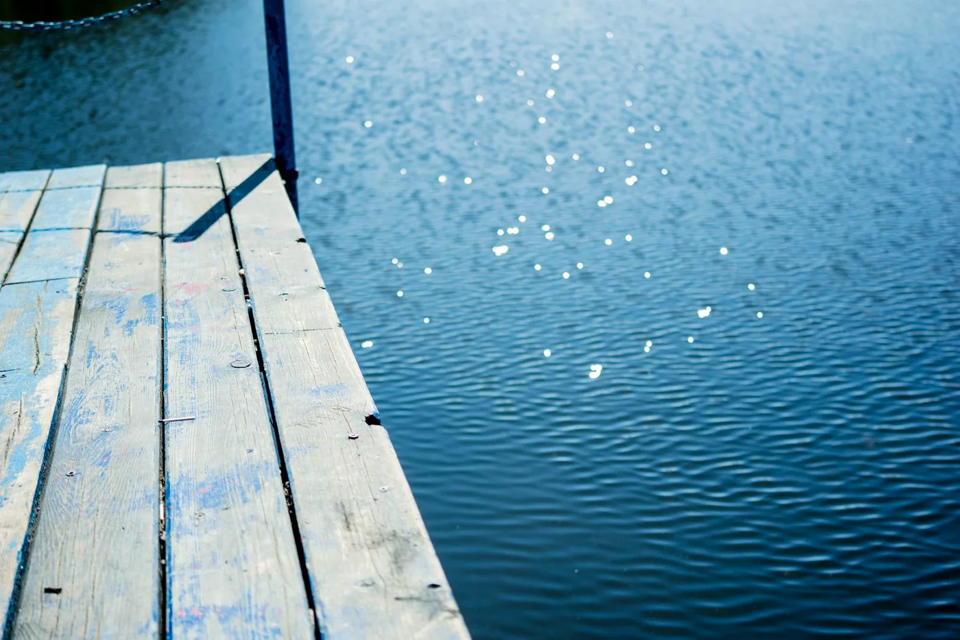 Wooden dock reaching out over a calm blue inland lake on a summer morning